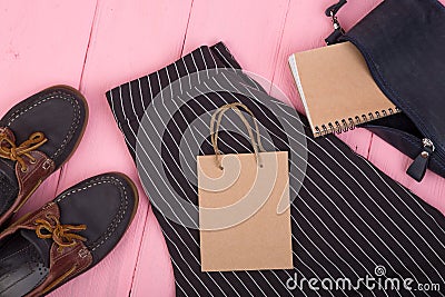 bag, trousers, shoes, gift bag, note pad on pink wooden background Stock Photo