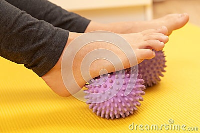 Female feet and purple prickly massage balls Stock Photo