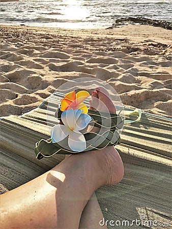 Female feet on the sand sith a Hawaiian, flower band Stock Photo