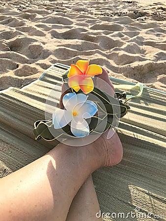 Female feet on the sand sith a Hawaiian, flower band Stock Photo