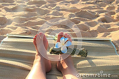 Female feet on the sand sith a Hawaiian, flower band Stock Photo