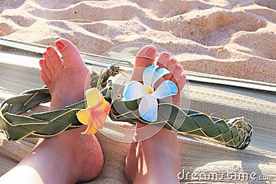 Female feet on the sand sith a Hawaiian, flower band Stock Photo