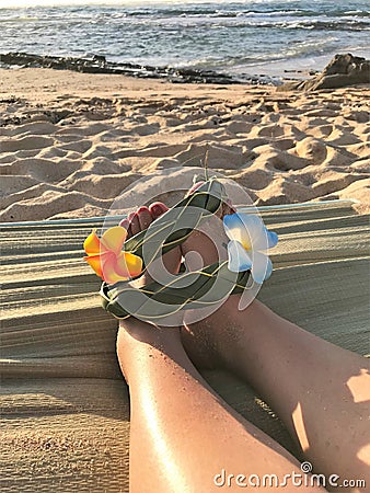 Female feet on the sand sith a Hawaiian, flower band Stock Photo