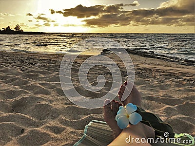 Female feet on the sand sith a Hawaiian, flower band Stock Photo