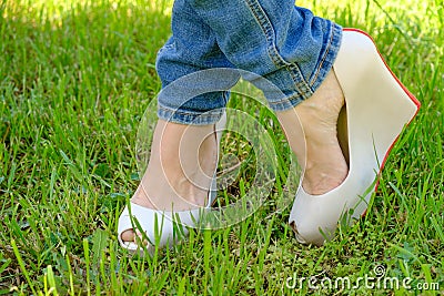 Female feet in shoes with wedge heels on green grass Stock Photo