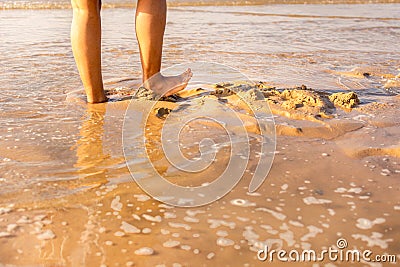 Female Feet soaking in the beach sand. orange golden sunlight Stock Photo