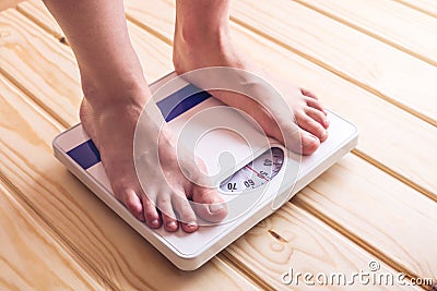 Female feet standing on mechanical scales for weight control on wooden background. Concept of slimming and weight loss Stock Photo