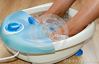 Female feet in a vibrating foot massager. Electric massage foot bath. Relax after work Stock Photo