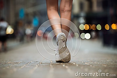 Female feet wearing sneakers running in city street. Woman with beautiful legs running in city at morning Stock Photo