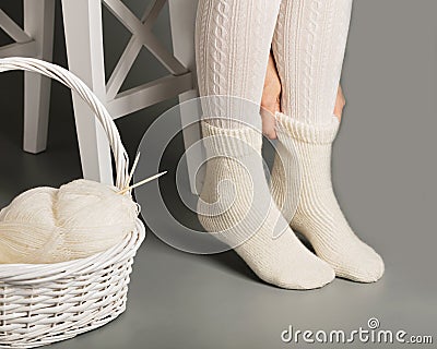 Female feet in white knitted stockings and socks near the basket Stock Photo