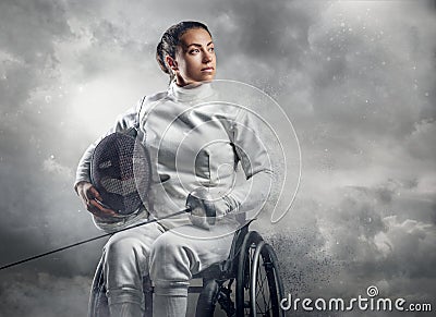 Female fencer in wheelchair with safety mask of a face holding rapier. Stock Photo