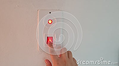 Woman switching off red button light on white wall Stock Photo