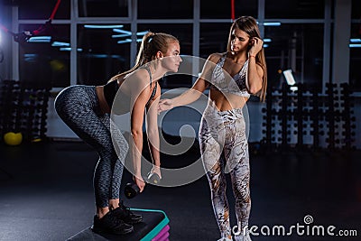 Female fitness instructor conducts personal training. Young attractive woman does deadlift on a platform with dumbbells Stock Photo