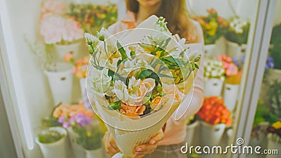 Female florist makes flower bunch, she cuts off wrapping paper w Stock Photo