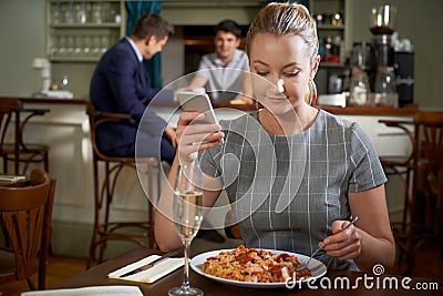 Female Food Blogger Posting Online Review Of Restaurant Meal Using Mobile Phone Stock Photo