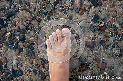 Female foot on a background of sea water. Stock Photo