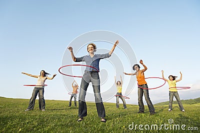 Female Friends Playing With Hula Hoop Against Sky In Park Stock Photo