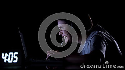 Female gamer in headset playing video games late at night, computer addiction Stock Photo