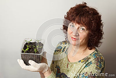 A female gardener shows a pot with sprouts after a pick Stock Photo