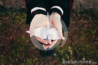 Female girl hands holding origami paper crane bird with background of grass, girl wear japanese school uniform Stock Photo