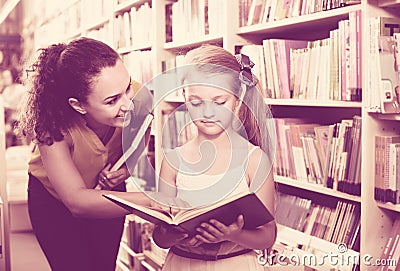 Female with girl in school age looking in open book Stock Photo