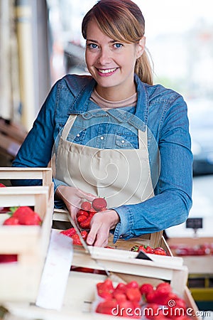Female grocer unpacking crates strawberries Stock Photo