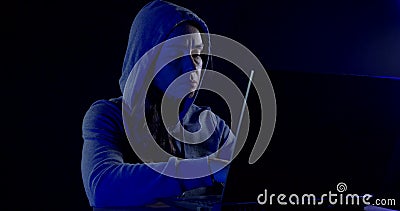 Female hacker sitting in the dark with his laptop and tries to crack the code software. Colored neon lights. Stock Photo