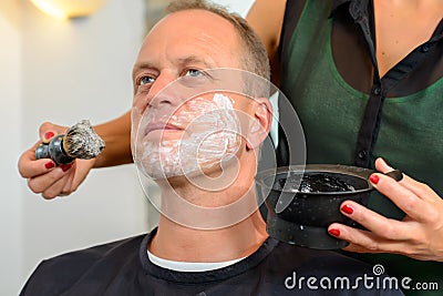 Female hairdresser shaving beard of man Stock Photo