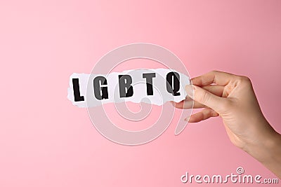 Female hand with abbreviation LGBTQ on color background Stock Photo