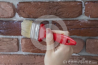 Female hand applies varnish to a decorative facing brick Stock Photo