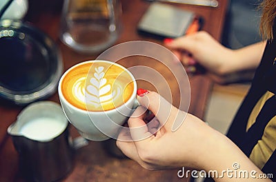 Female hand barista with a white cup of fragrant cappuccino with Stock Photo