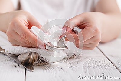 Female hand cleaning spotty silverware with a cleaning product a Stock Photo