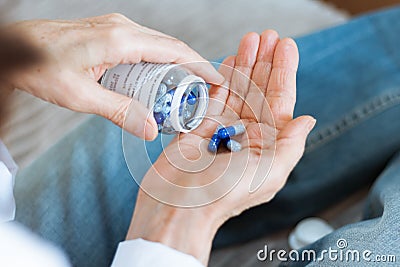 Female hand close up holding a medicine, elderly woman hands with pill on spilling pills out of bottle Stock Photo