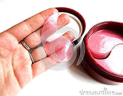 In a female hand a cosmetic patch for the face. Cosmetic eye patches in a jar on a white background. Face skin care. Modern Stock Photo