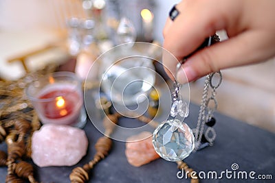 female hand with crystal glass ball, pendulum swings over astrologer's table, Harmony with meditation, self-discovery Stock Photo