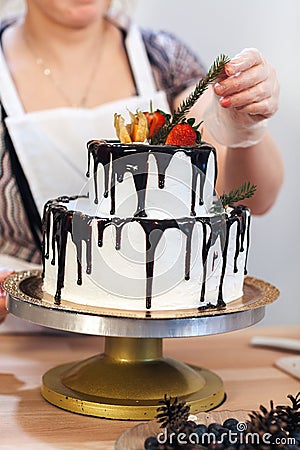 Female hand decorates a white cream cake with fruit, close-up Stock Photo