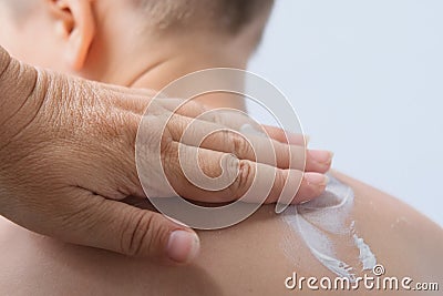 Female hand gently lubricates the back of a child, boy 6-7 years old with sunscreen, body hygiene concept, sunburn, daily morning Stock Photo