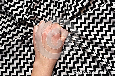 Female hand grasping or clutching silk bed sheet with geometric print in ecstasy. Sex, orgasm, sexual pleasure concept Stock Photo