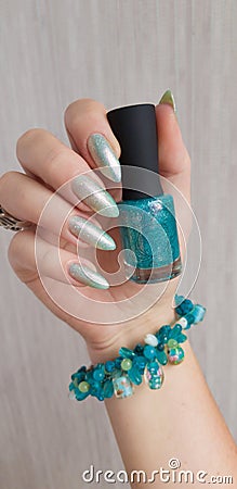 A female hand with grey long nails holds a bottle Stock Photo