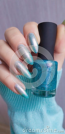 A female hand with grey long nails holds a bottle Stock Photo