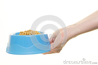 Female hand holding blue plastic feeding bowl filled with cat kibble isolated on a white background Stock Photo