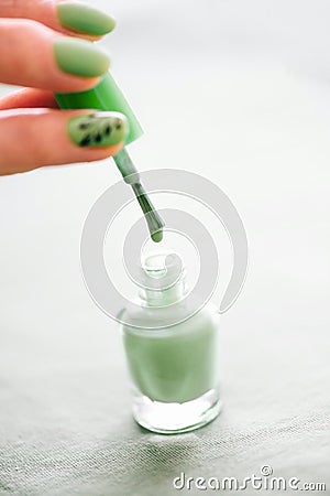 Female hand holding brush of bottle nail polish green color. Stock Photo