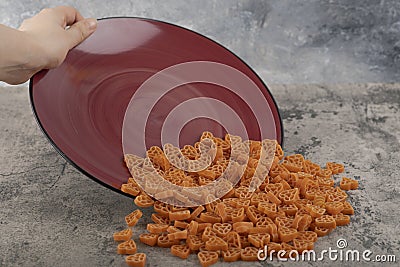 Female hand holding burgundy plate macaroni on marble background Stock Photo