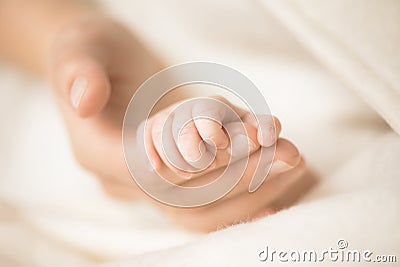 Female hand holding her newborn baby`s hand. Mom with her child. Maternity, family, birth concept. Copy space for your Stock Photo