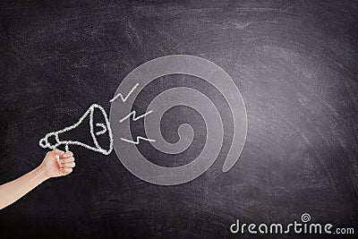 Female hand holding megaphone white chalk icon on blackboard for announcement and advertisement. Stock Photo
