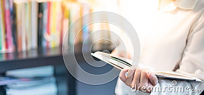 Female hand holding notebook with the space book for note or remark and sitting in the library Stock Photo