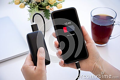 female hand holding phone with red discharged battery on screen Stock Photo