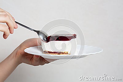 Female hand holding plate and spoot with sweet cheese dessert with cherry Stock Photo