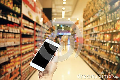 Female hand holding smartphone at supermarket and checking shopping list, Online shopping in mobile phone application concept. Stock Photo