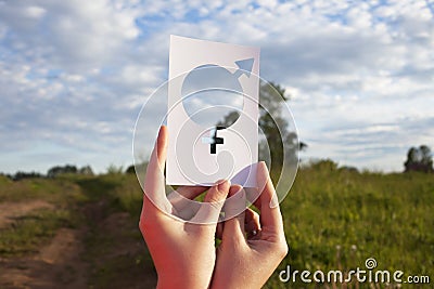 Female hand holding a symbol of gender equality against the background of blue sky with clouds Stock Photo